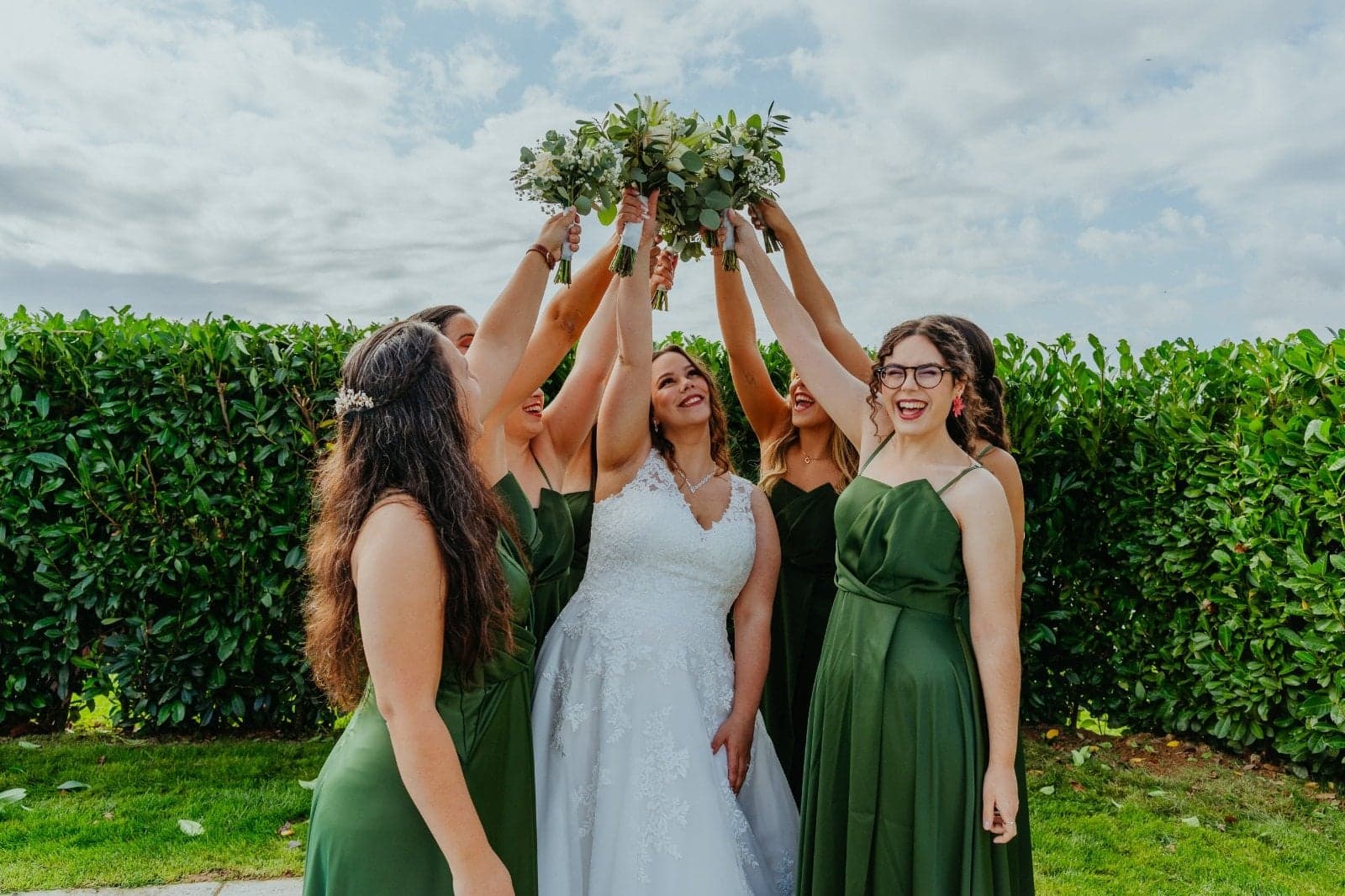 Noiva e damas de honor de verde a erguer os bouquets